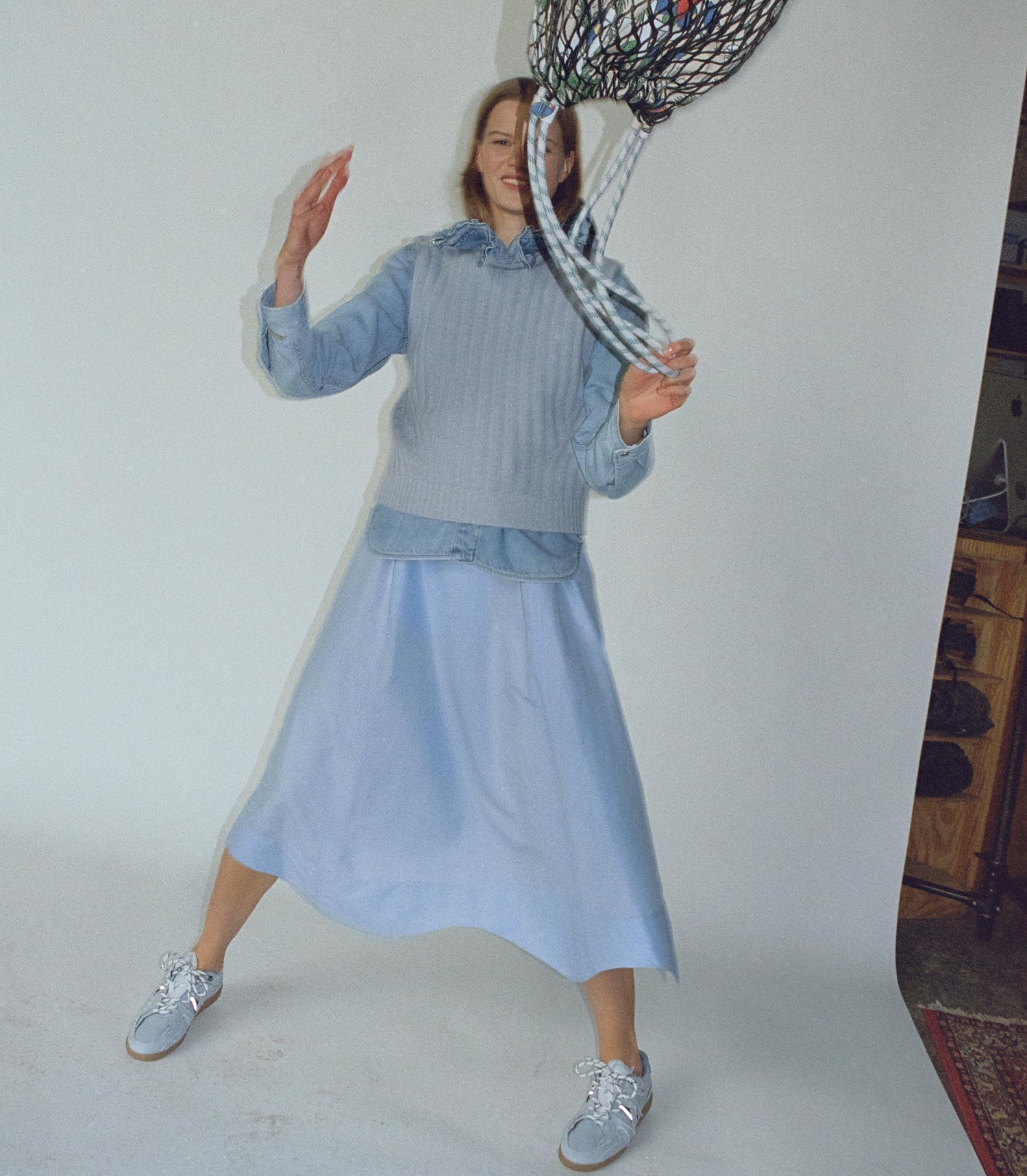 Model mit blauem Kleid wirft Tasche in die Luft