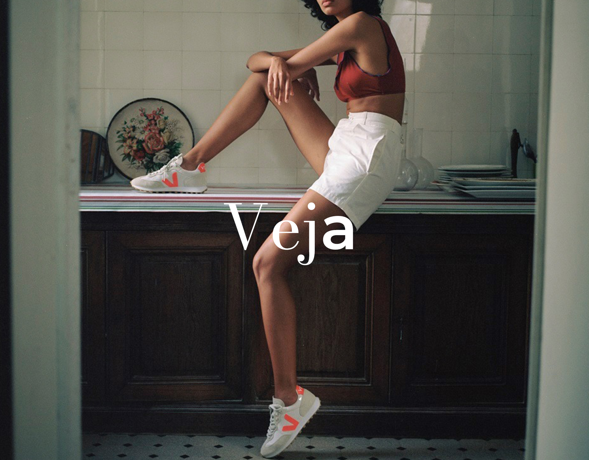 Model sitzt auf Küchentheke und trägt Veja Sneakers