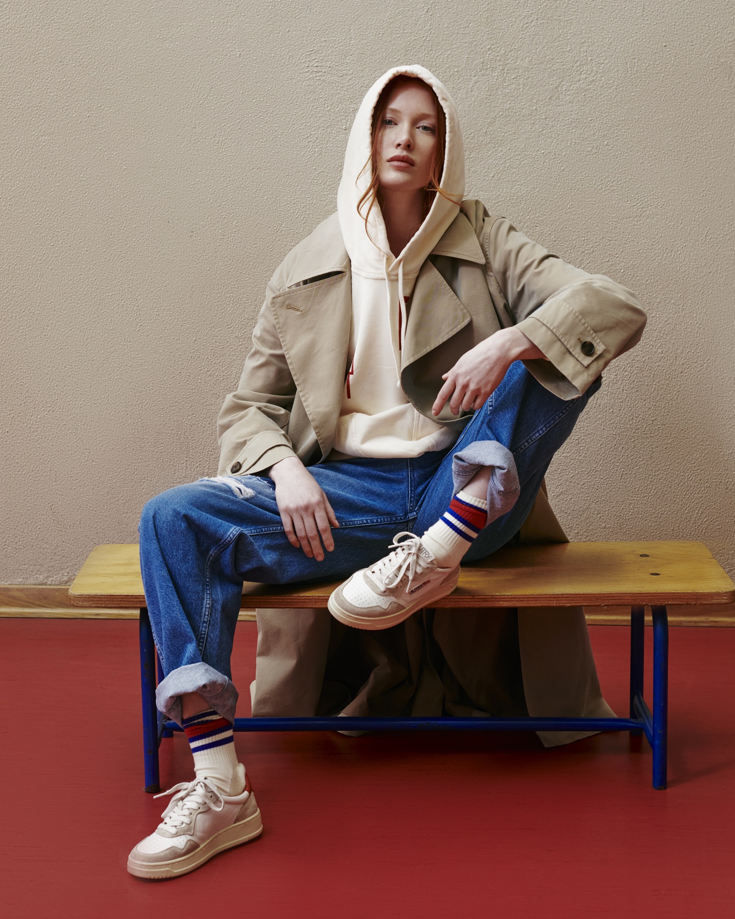 Model trägt Autry Sneakers und sitzt auf einer Holzbank